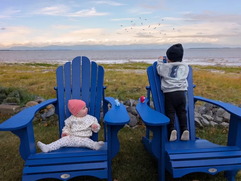 Deux enfants dans les chaises bleues devant le fleuve